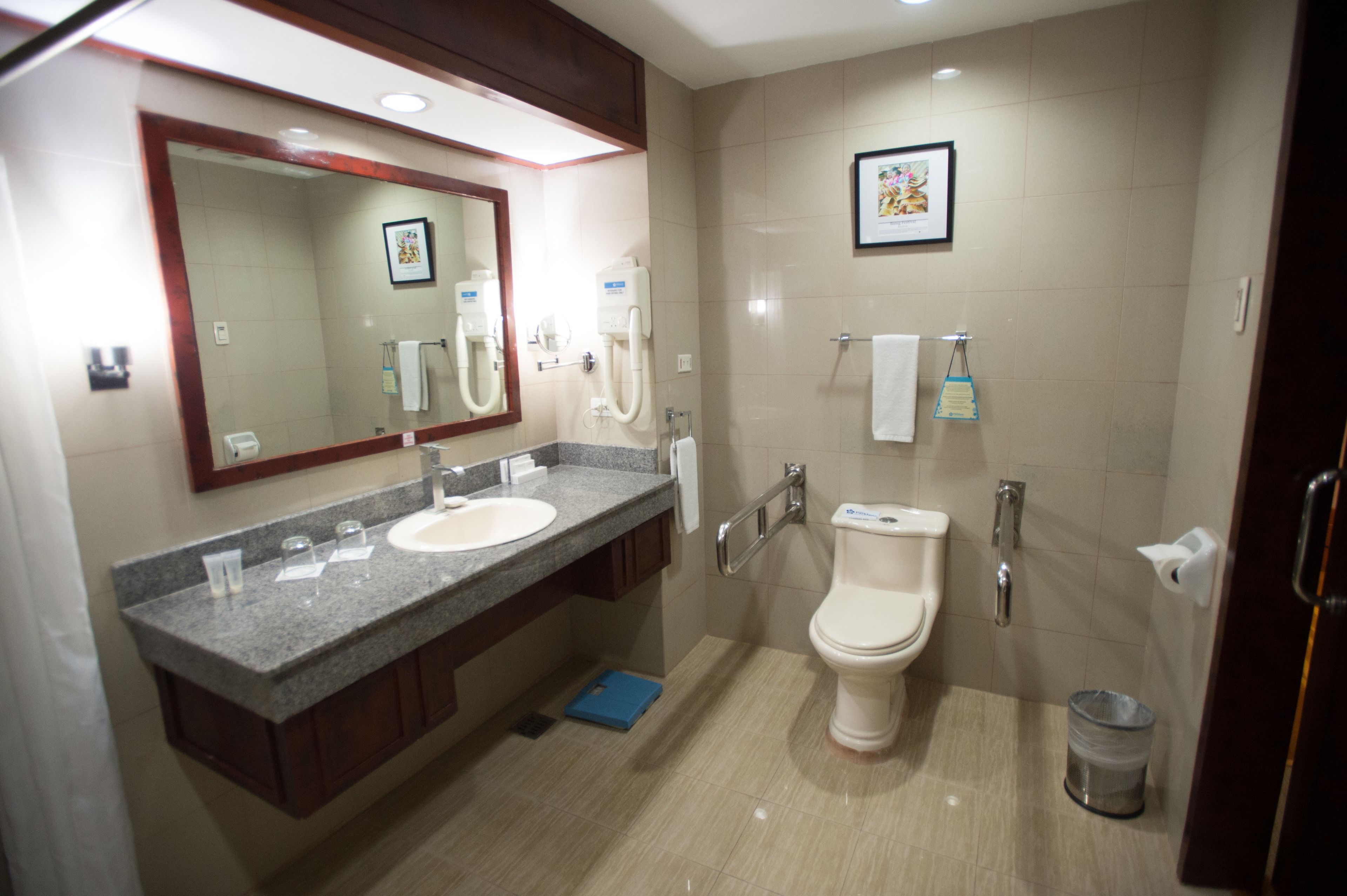 Uma casa de banho moderna com duas pias, um espelho grande, uma sanita e um contentor de lixo.