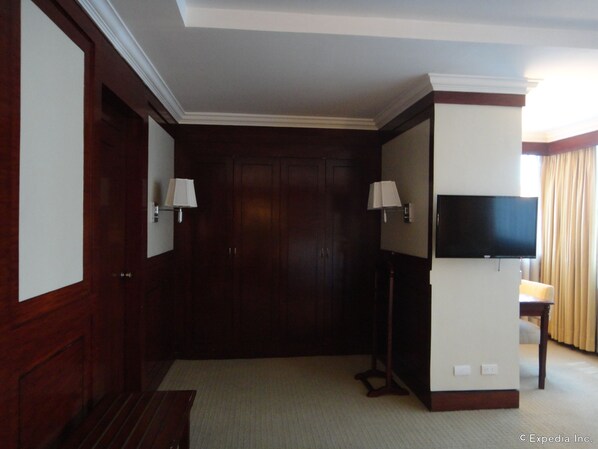 A hotel room with a wooden door, a flat-screen TV mounted on the wall, and two wall-mounted lamps. - Cebu Parklane International Hotel (Cebu City)