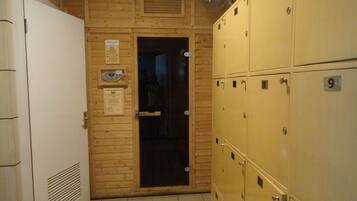 A hotel room with wooden paneling, a white door, and a row of numbered yellow lockers.