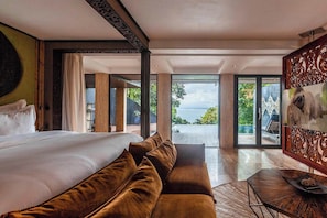 Une chambre spacieuse avec un grand lit, un canapé et une vue sur un plan d’eau.