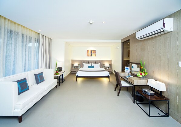 A modern hotel room with a bed, a sofa, a desk, and a chair.