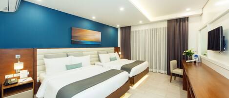 A modern hotel room with two beds, a desk, a chair, a TV, and an air conditioning unit.