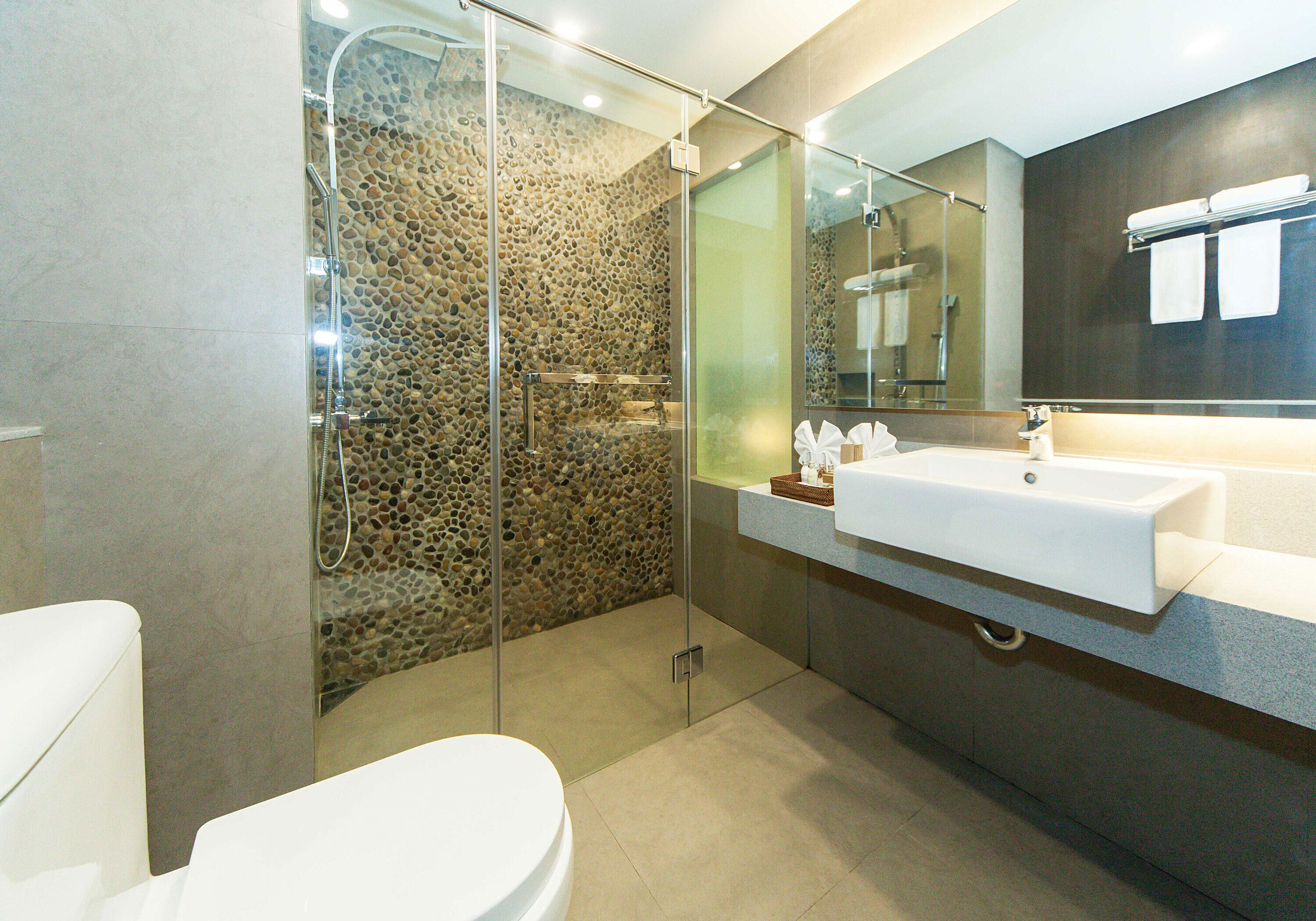 A modern bathroom with a glass-enclosed shower, a white sink, and a large mirror.