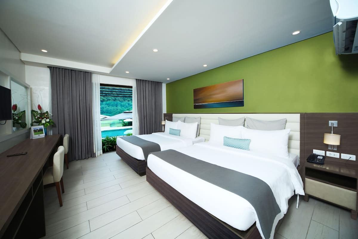 Une chambre d’hôtel avec deux lits, un bureau et une vue sur la piscine.