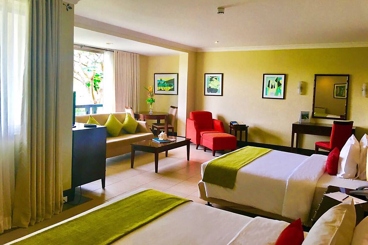 Une chambre d’hôtel avec deux lits, un bureau, une chaise, une télévision et une fenêtre avec des rideaux.
