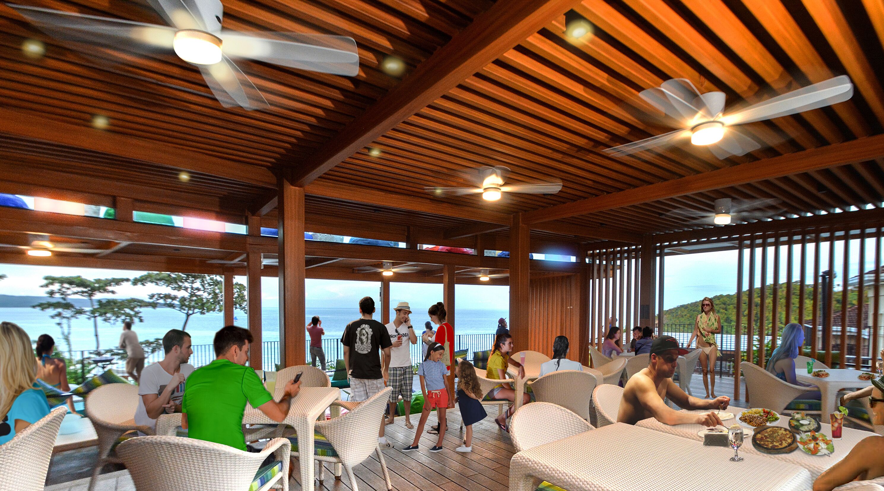 An outdoor dining area with wicker chairs and tables, ceiling fans, and a view of the ocean.