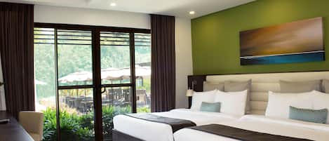 A hotel room with two beds, a desk, and a view of an outdoor area with umbrellas.