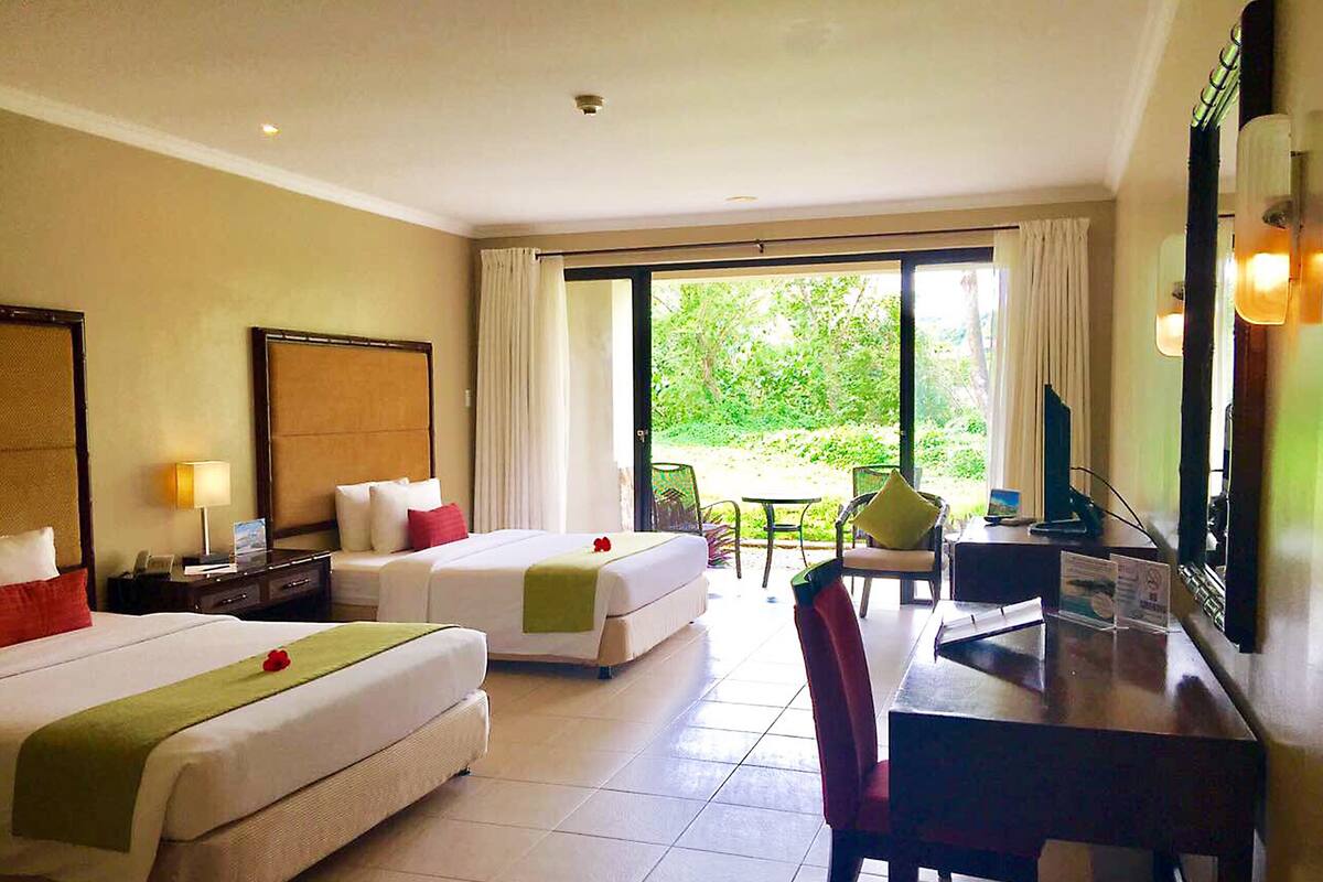 Une chambre d’hôtel avec deux lits, un bureau, une chaise, une télévision et une vue sur la verdure.
