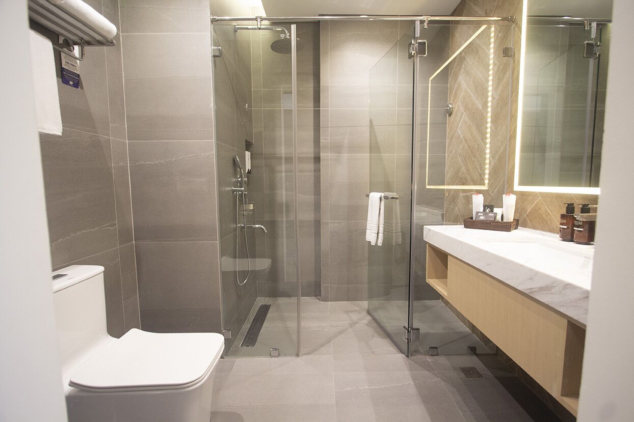 Un baño moderno con ducha envuelta en vidrio, inodoro blanco y tocador con espejo.