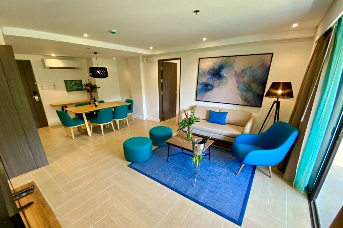 Un salon moderne comprenant un canapé, des fauteuils, une table basse et un coin repas avec une table et des chaises.