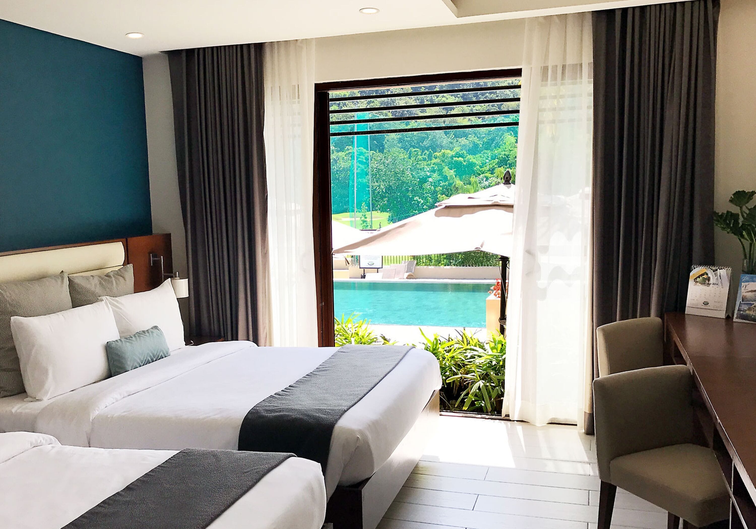 Camera d'albergo con un letto grande, una scrivania e vista su una piscina.