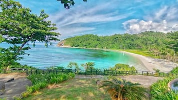 Un paysage côtier avec une plage, une végétation luxuriante et un ciel dégagé.