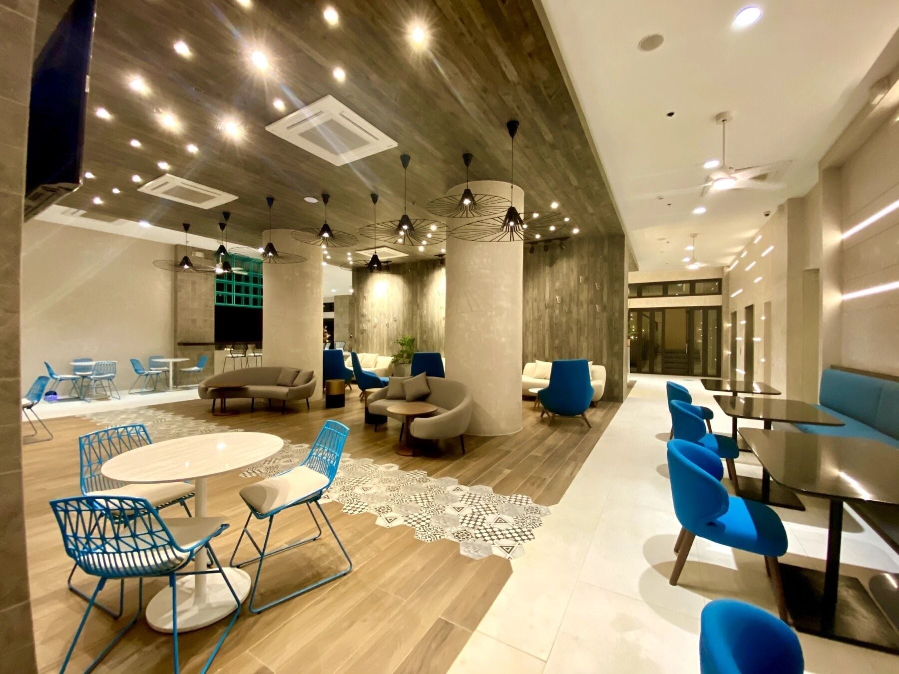 A modern lounge area with round tables, blue chairs, and sofas.