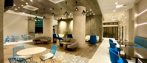 A modern lounge area with round tables, blue chairs, and sofas.