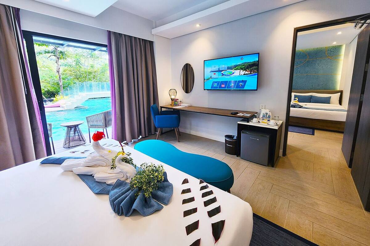 Une chambre d’hôtel moderne dotée d’un grand lit, d’un bureau, d’une télévision et offrant une vue sur l’extérieur.