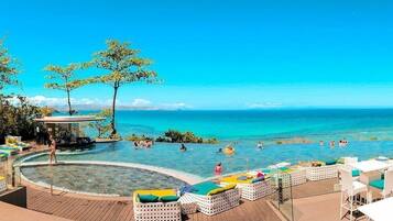 Relax by the ocean with a poolside view, lounge chairs, and shaded areas.