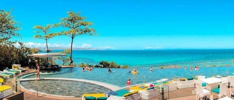 Ein Poolbereich mit Liegestühlen und einer Laube mit Blick auf das Meer.