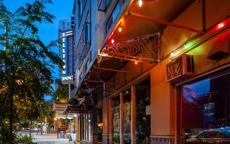 A hotel with a neon sign, outdoor seating, and a storefront with a neon sign.