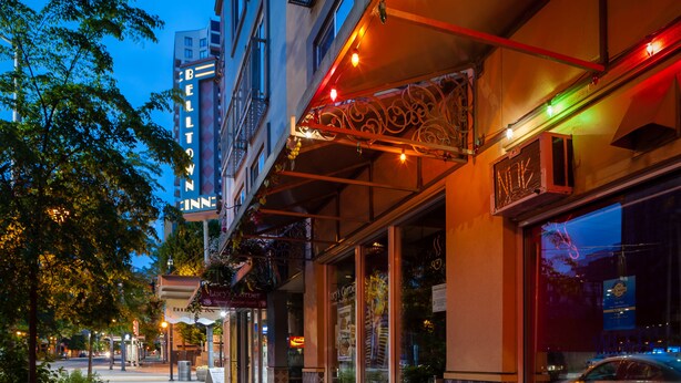 A hotel with a neon sign, outdoor seating, and a storefront with a neon sign. - The Belltown Inn (Seattle)