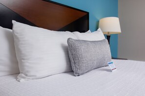 A neatly made bed with white and gray pillows, a wooden headboard, and a lamp on a nightstand. - The Belltown Inn (Seattle)