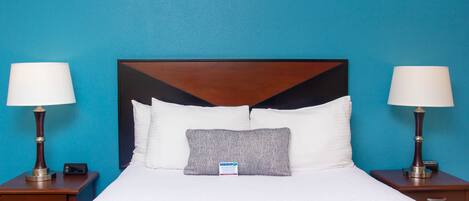 A hotel room with a large bed, two bedside tables, and a nightstand.