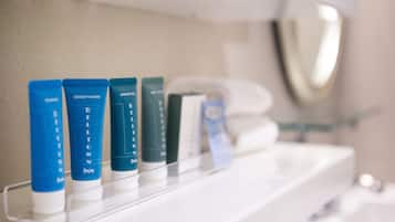 A row of toiletries on a white shelf in a bathroom.
