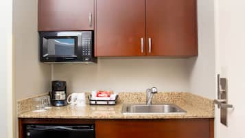 A kitchen with a microwave, coffee maker, and a sink.
