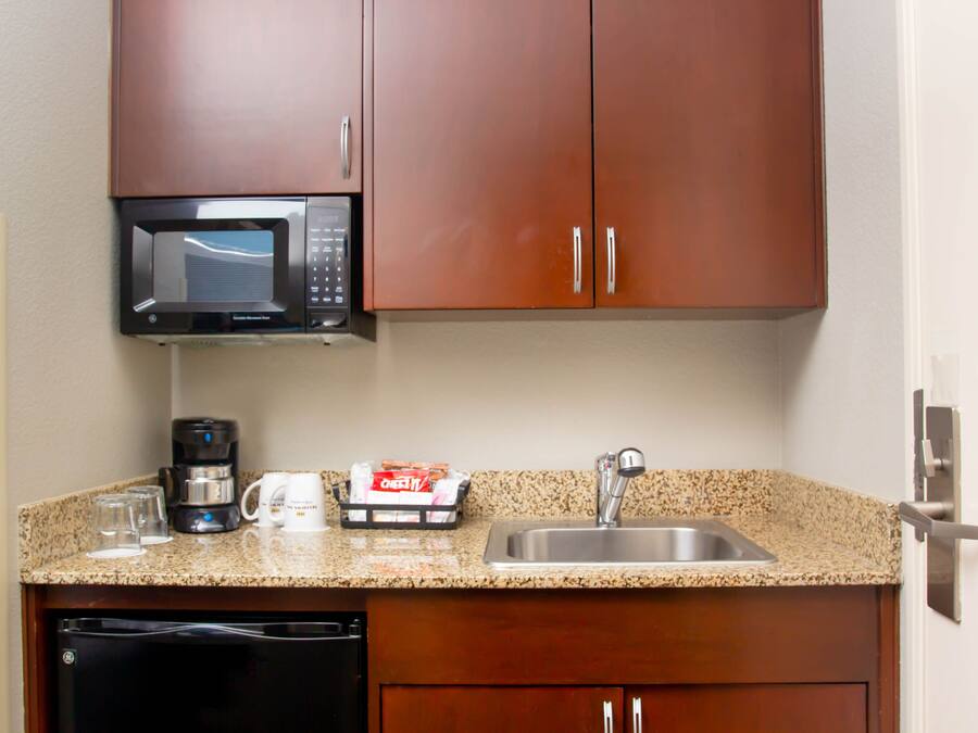 A kitchen with a microwave, coffee maker, and a sink.