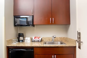 A kitchen with a microwave, coffee maker, and a sink.