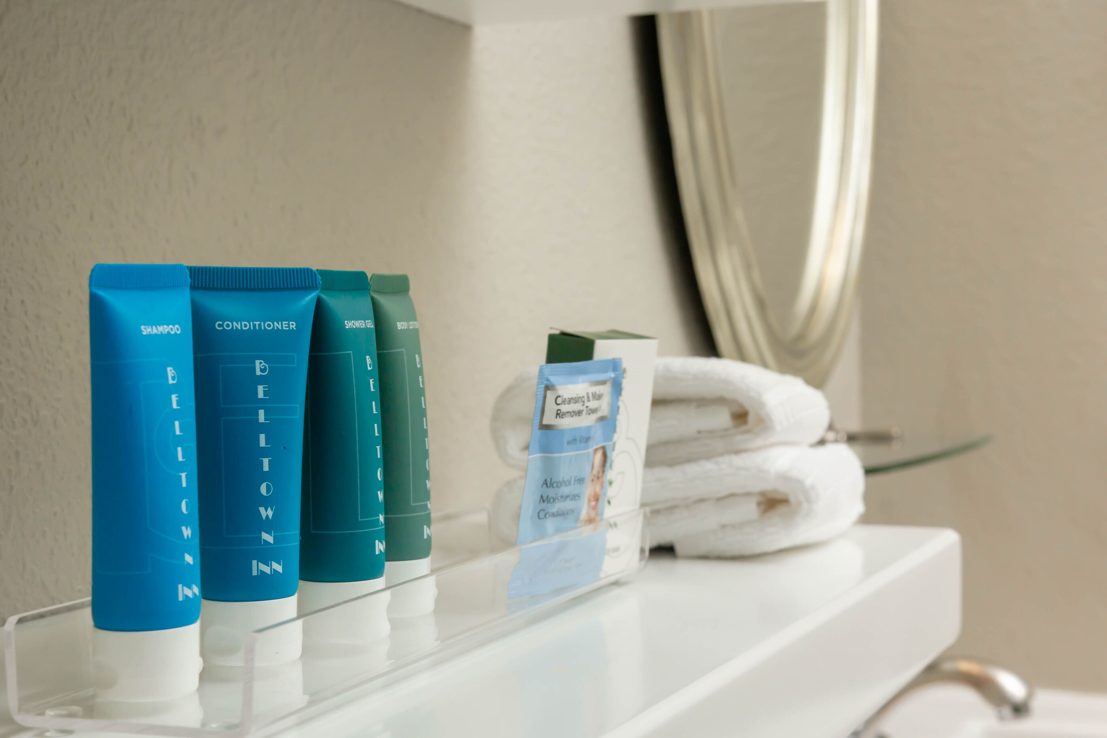 Productos de baño en un estante, incluyendo champú, acondicionador, gel de ducha y jabón limpiador.