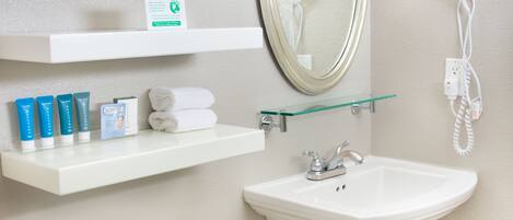 A bathroom with a toilet, sink, mirror, and shelves with toiletries.