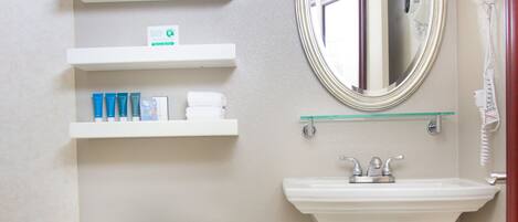 A bathroom with a toilet, sink, mirror, towel rack, and shelves with toiletries.