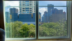 A window with a view of tall buildings and dense foliage. - The Belltown Inn (Seattle)