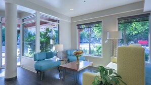 A modern hotel lobby with a blue sofa, a wooden table with a vase of flowers, and a lamp. - The Belltown Inn (Seattle)
