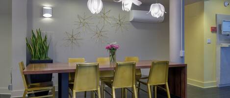 A modern dining area with a long wooden table, yellow chairs, and decorative wall art.
