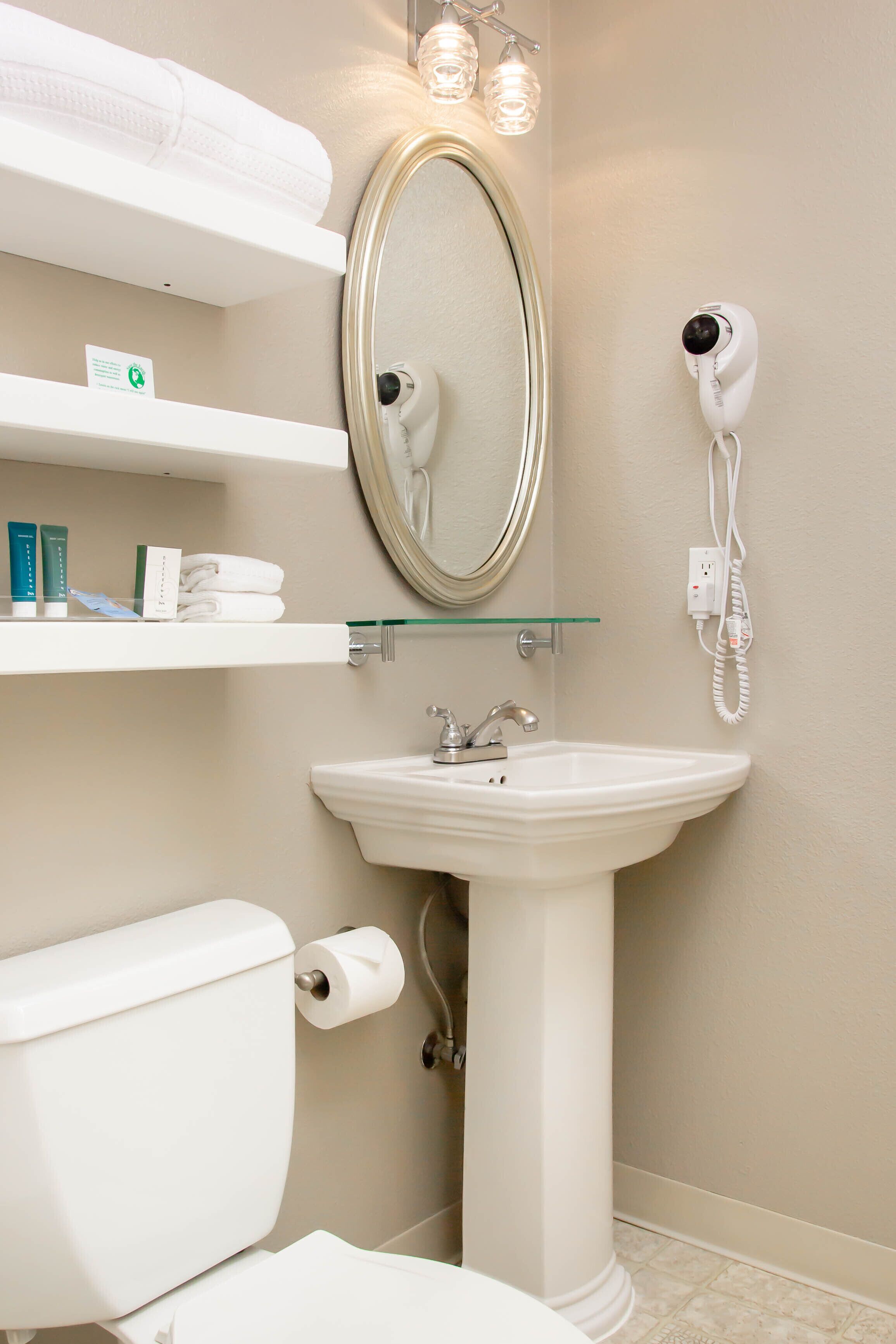 A bathroom with a toilet, sink, and a hairdryer mounted on the wall.
