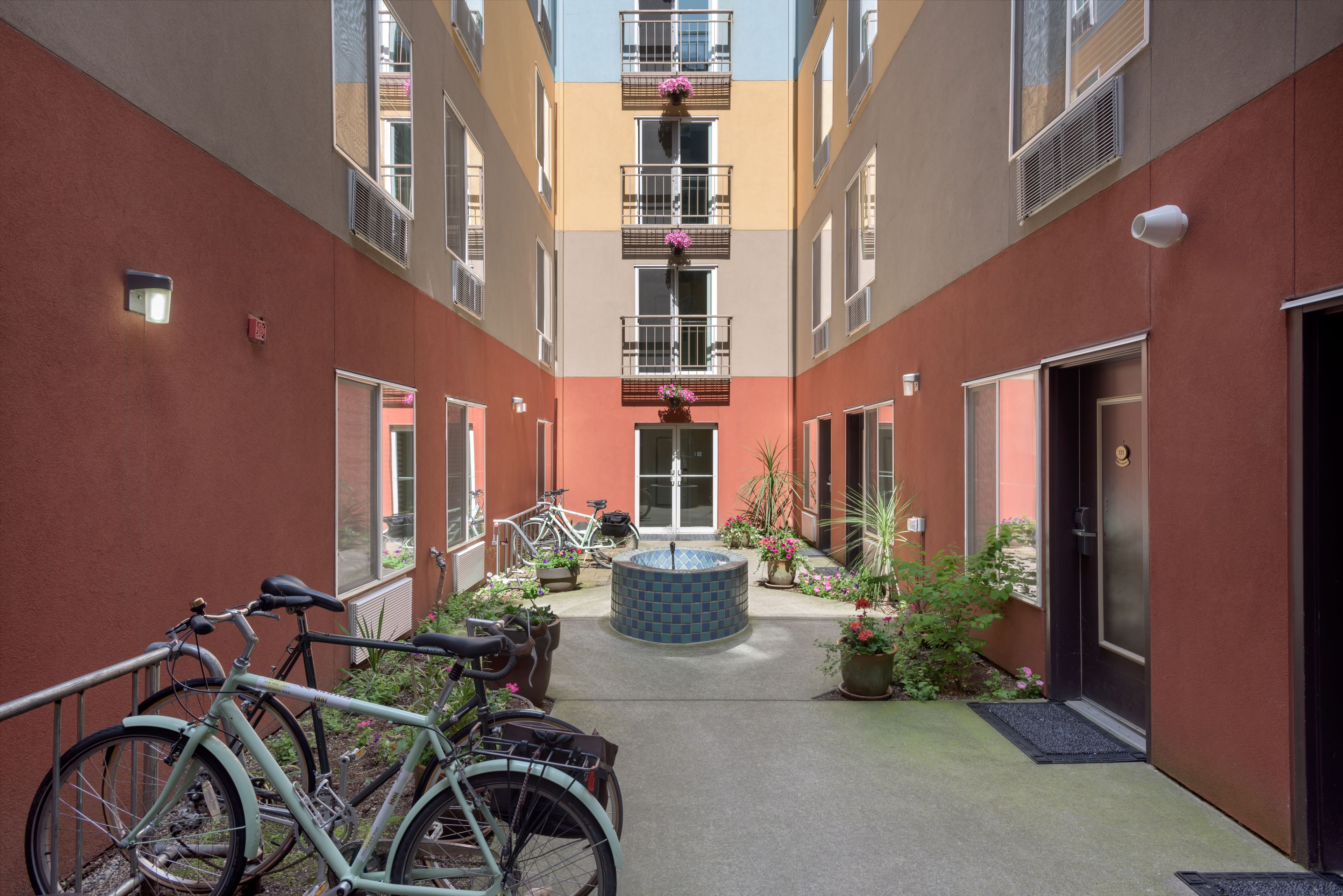 A courtyard with bicycles, a central water feature, and potted plants.