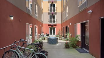 A courtyard with bicycles, a central water feature, and potted plants.