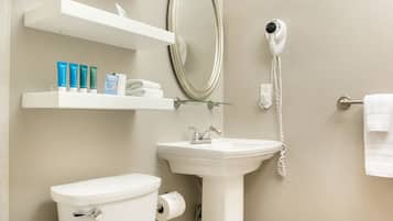 A bathroom with a toilet, sink, and a hairdryer mounted on the wall.