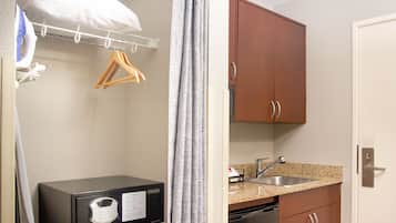 A compact kitchen with a microwave, sink, and wooden cabinets.