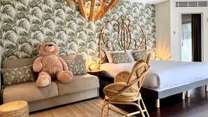 Un dormitorio con cama, sofá, sillón y un gran oso de peluche.