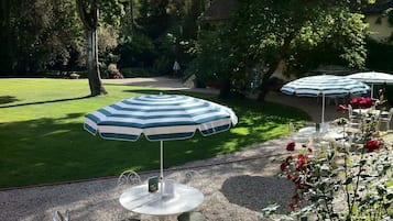 A patio area with a round table and chairs, surrounded by a gravel path.