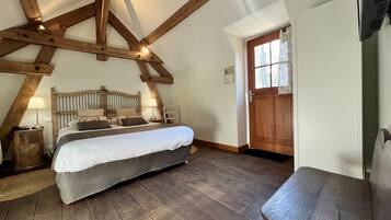 Ein Schlafzimmer mit Holzboden, einem Bett, einem Sessel und einer Tür.
