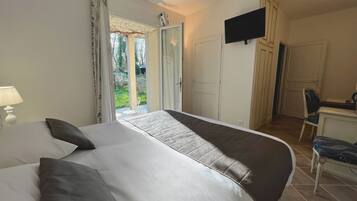 Un dormitorio con una cama grande, televisión, escritorio y una silla.