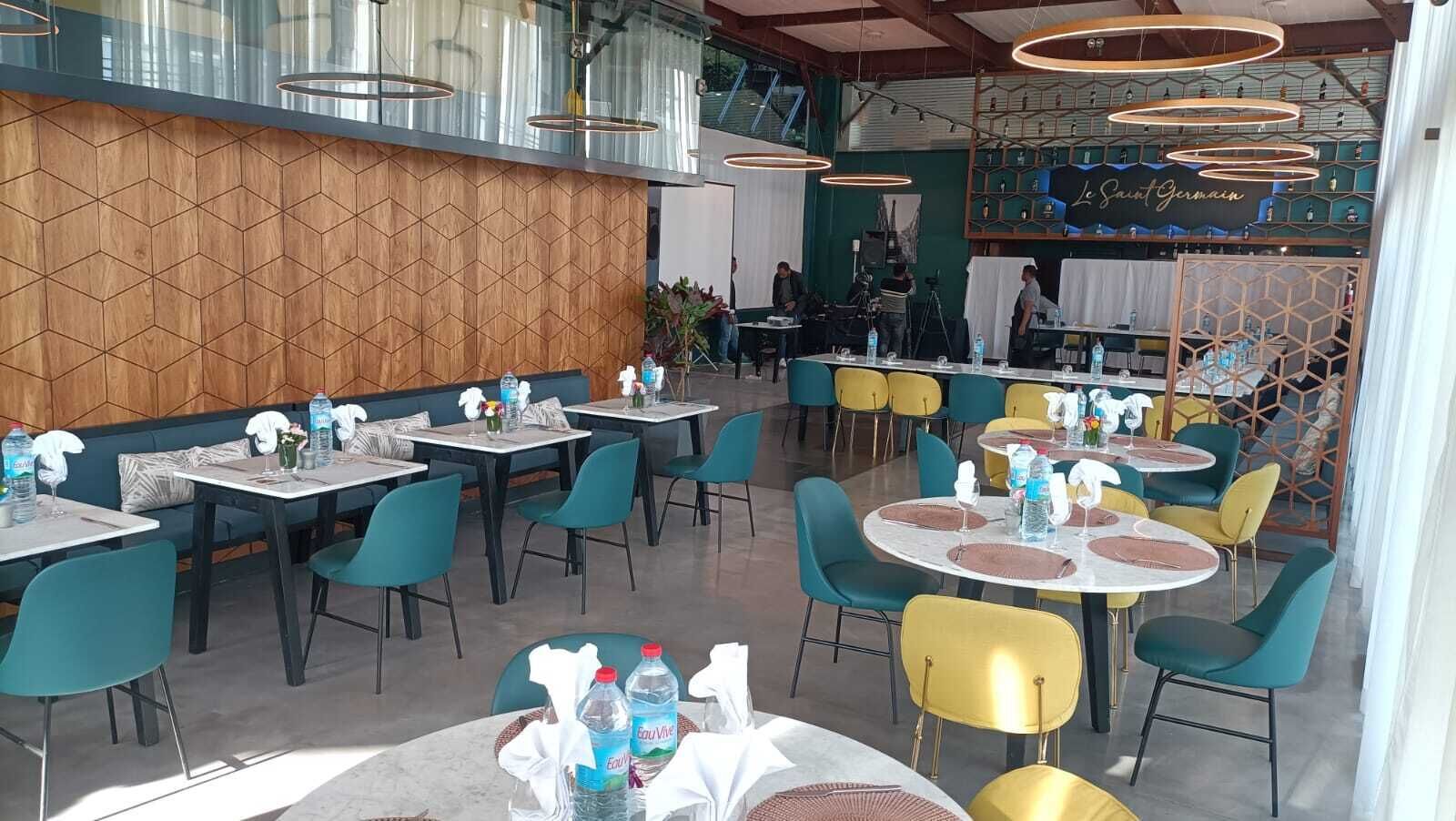 A restaurant with multiple tables and chairs, some with water bottles and napkins.