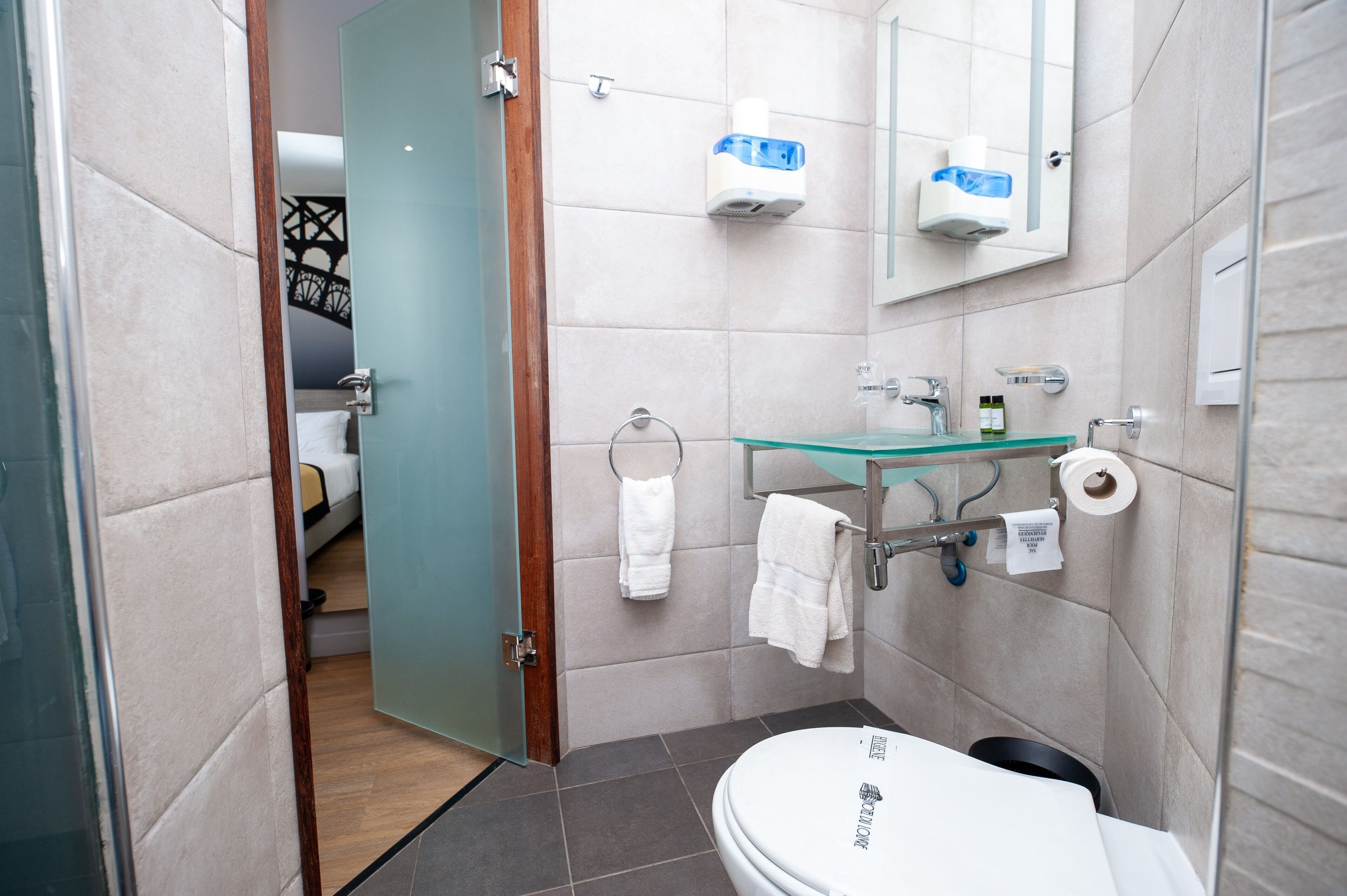 Un bagno moderno con lavabo in vetro, un water e una zona doccia.