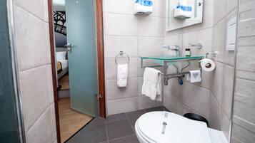 Un bagno moderno con lavabo in vetro, un water e una zona doccia.