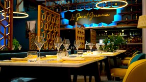 A restaurant interior with tables set for dining, a bar area with shelves of bottles, and a decorative sign that reads "Le Saint-Germain".