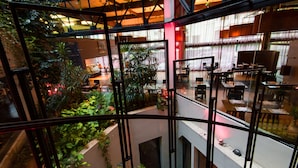 A multi-level atrium with indoor plants, glass railings, and dining areas.