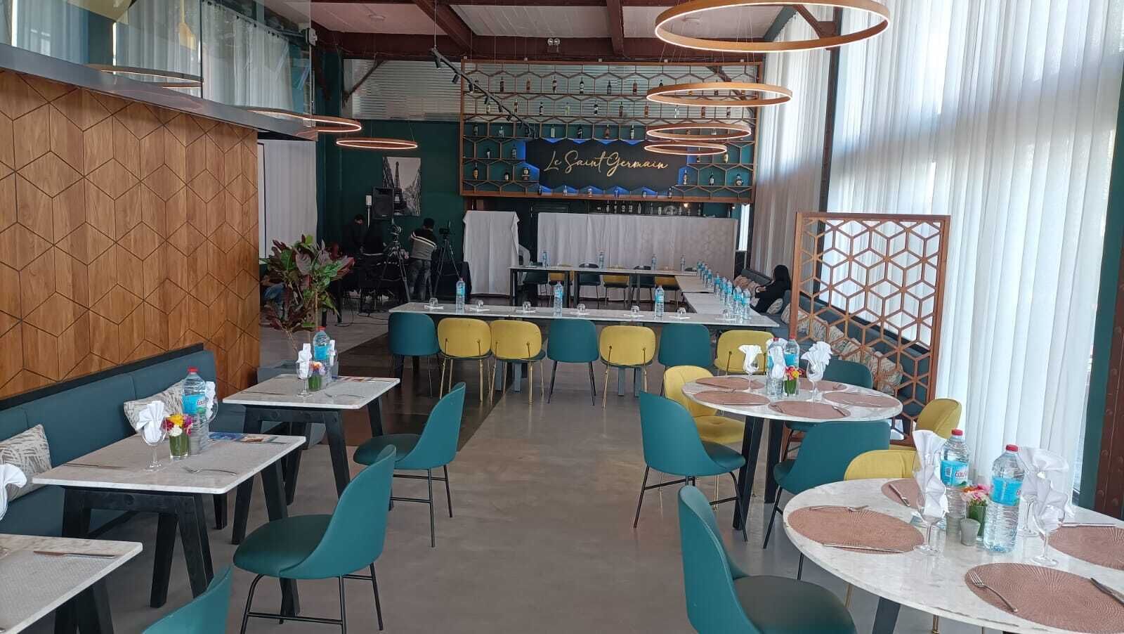 A restaurant with multiple tables and chairs, a bar area, and a decorative wall with the name 'Saint Germain'.